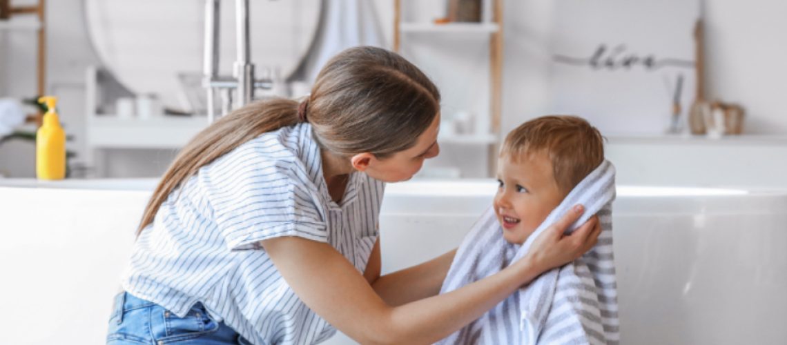 mother drying her child in bathroom with a canvas print behind them